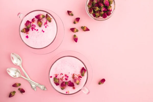 Pembe yüzeyde iki kapta gül ay sütü manzarası. Boşluğu kopyala.