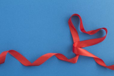 Mavi arkaplanda kırmızı kalp şekilli kurdele kopyalama alanı
