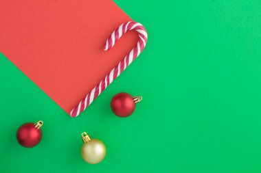 Kırmızı yeşil yüzeyde noel karamelli baston ve topların en üst görüntüsü. Boşluğu kopyala.