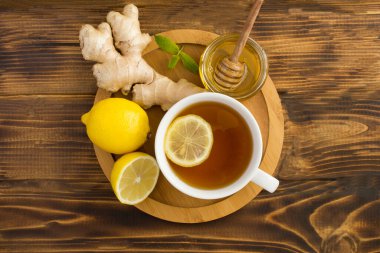 Tahta kesme tahtasının üstünde limonlu, ballı ve zencefilli yeşil çay.