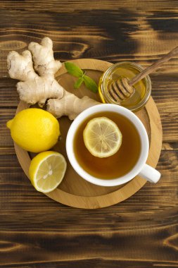 Tahta kesme tahtasının üstünde limonlu, ballı ve zencefilli yeşil çay.