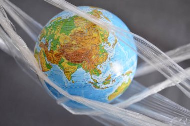 Toprak bir plastik plastik tek kullanımlık ambalaj, karanlık bir arka plan üzerinde bekletilir. Polietilen Plastik tarafından çevre kirliliği kavramı atık, çevre sorunları.