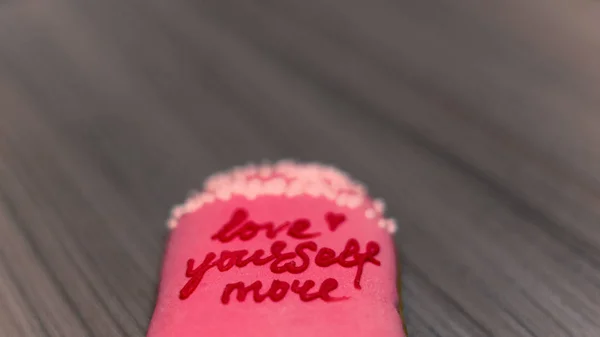 Love yourself more - inscription on pink and wooden background