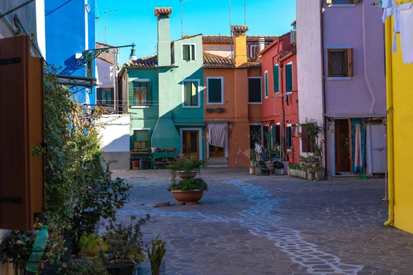 Colorful houses of Burano Island. Venice. Typical street with hanging laundry at facades of colorful houses