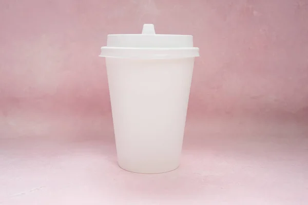 Coffee packing mockup - white paper cup with white cap on light pink background with copy space