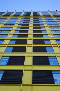 Mavi gökyüzüne karşı geometrik detayları ile yüksek beton modern yüksek binanın dikey görünümü