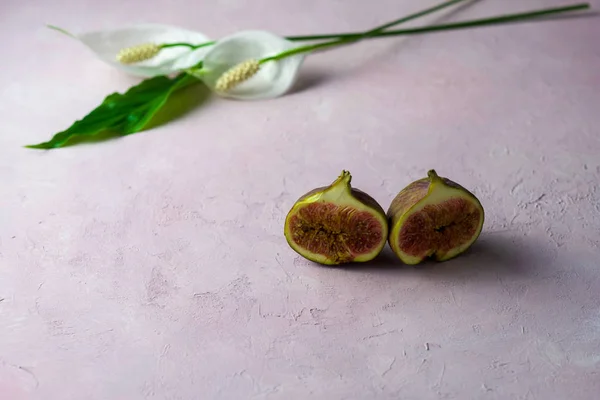 Inteiros frescos e cortar figos com algumas flores em um fundo de mármore rosa claro com espaço de cópia. Foco selecionado — Fotografia de Stock