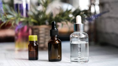 Kahverengi, damlalıklı berrak gözlükler, koyu arka planda organik yeşil yapraklar. Bitkisel ekstresi ile serum veya uçucu yağ