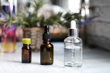 Kahverengi, damlalıklı berrak gözlükler, koyu arka planda organik yeşil yapraklar. Bitkisel ekstresi ile serum veya uçucu yağ