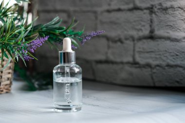 damlalık ile açık cam, koyu arka plan üzerinde organik yeşil yaprakları. Bitkisel ekstresi ile serum veya uçucu yağ