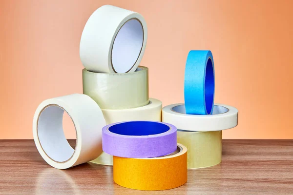 stock image Duct tape in assortment lies on table against background of orange wall.