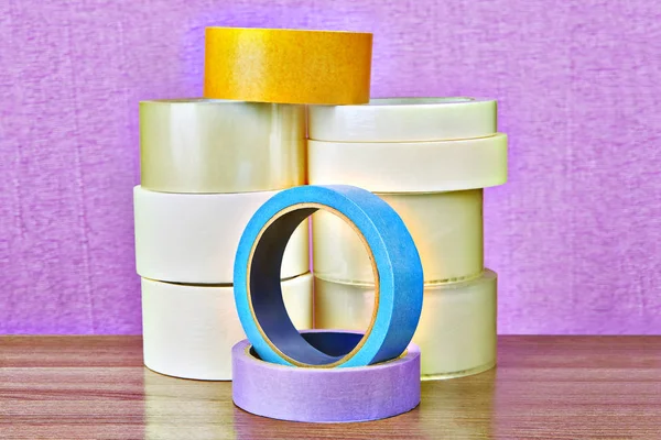 Set of transparent duct tape and colored masking paper tape on purple background.