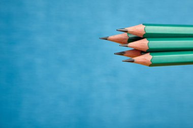 Grup mavi zemin üzerinde bir grafit çubuk ile ahşap bir kabuk beş aynı basit kalemler.