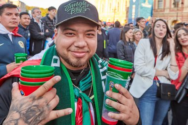 St. Petersburg, Rusya Federasyonu - 25 Haziran 2018: Yazıt orman çocuklar ve sembollerle fan İran Millî Futbol takımının şapkalı adam birkaç kağıt bardak bira altından tutarak gülümsüyor.