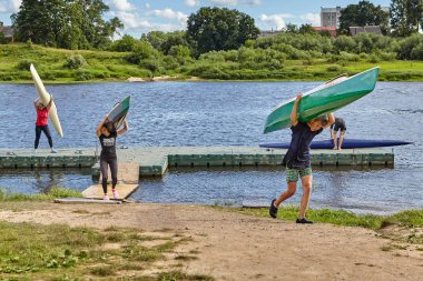 Polotsk, Beyaz Rusya - 6 Temmuz 2018: Genç adam ve kızlar Kano sırtlarında kaldırdı ve onları kürek eğitim sonra depolama için taşıdım.