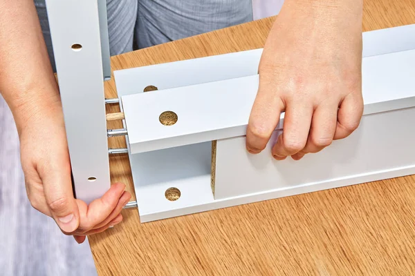 家具アセンブラー木製テーブルのパーツを接続して 別の側面からの つの側面およびピンからカム ボルト固定具が反対側の穴に挿入されます — ストック写真
