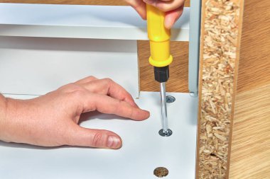 Tamirci tablo ahşap yüzeyine kadar bir deliğe somun sıkılaştırır, mobilya assembler onun ikinci el ile tablo parçası tutar.