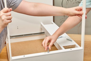 Tamirciler çekmeceyi parçası ile vidasını sabitleyin, onlardan biri ahşap masa yüzeyinin içine vida sıkılaştırır, diğeri mobilya tutar.