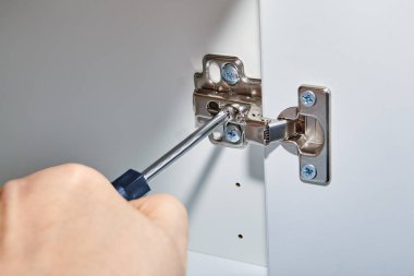 Bir tornavida ile araya hazır mobilya masaüstünün kapı açma mekanizmasını düzeltilmesi.