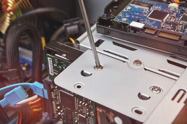 Hardware installation and upgrades of the unassembled computer system unit with help of screwdriver, close-up.