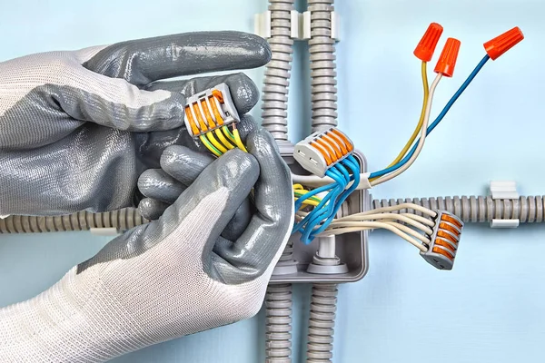 Electricista en guantes protectores monta caja de conexiones . — Foto de Stock