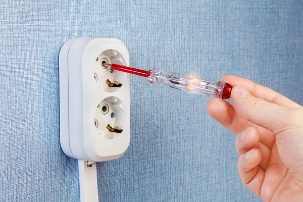 Comprobación de tensión en enchufe de pared con probador de electricidad . — Foto de Stock