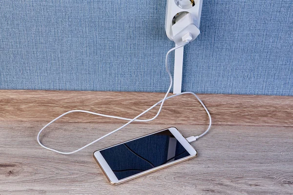 Smartphone está conectado ao carregador e deitado no chão . — Fotografia de Stock