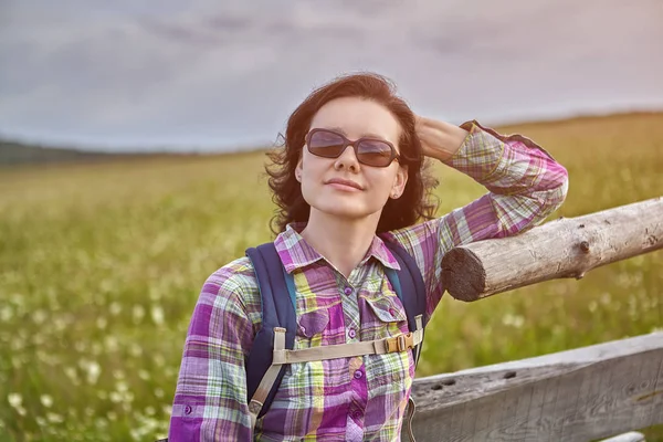 Een vrouw die op een houten hek is aanleunen. — Stockfoto