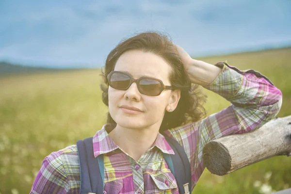 A woman in sunglasses stands by the fence. — Stock Photo, Image