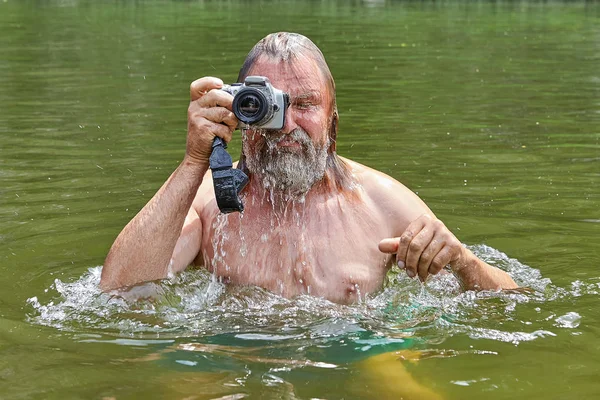 Vousatý muž si dělá fotky v řece. — Stock fotografie