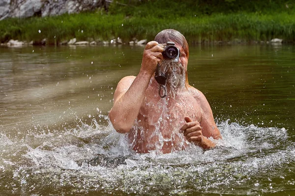 Volwassen man is met behulp van waterdichte camera in rivier. — Stockfoto