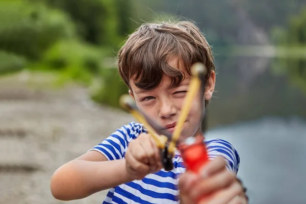 Menino com fisga na floresta está apontando . — Fotografia de Stock