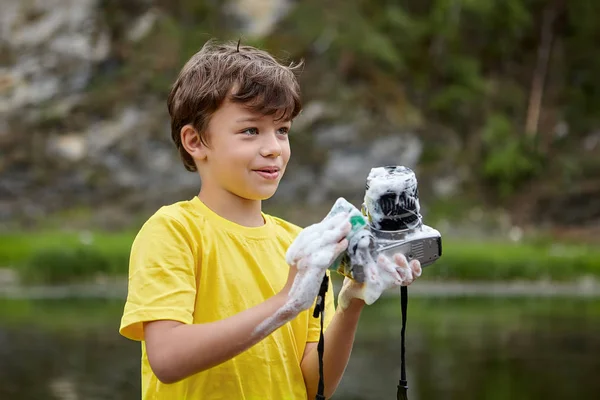 Jongen is het wassen van digitale camera. — Stockfoto