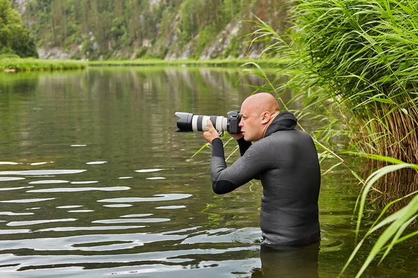 男は水の中に立って写真を撮る. — ストック写真