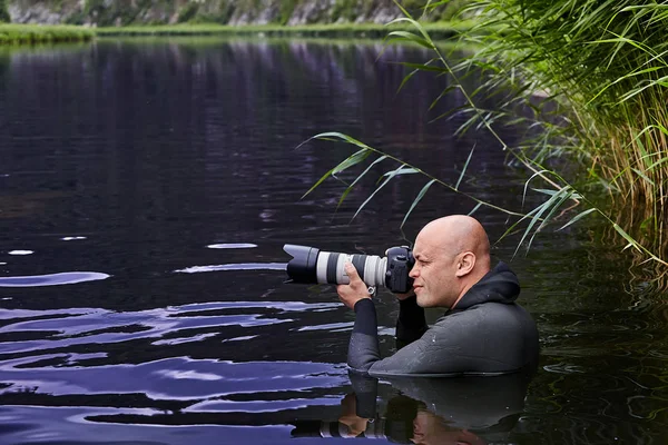 男は水の中に立って写真を撮る. — ストック写真