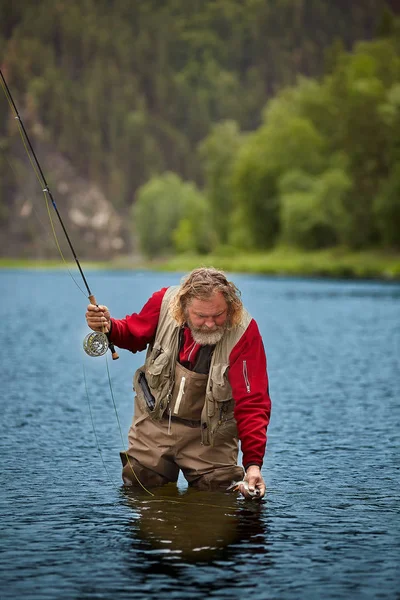 Mann mit Fisch beim Fliegenfischen gefangen. — Stockfoto