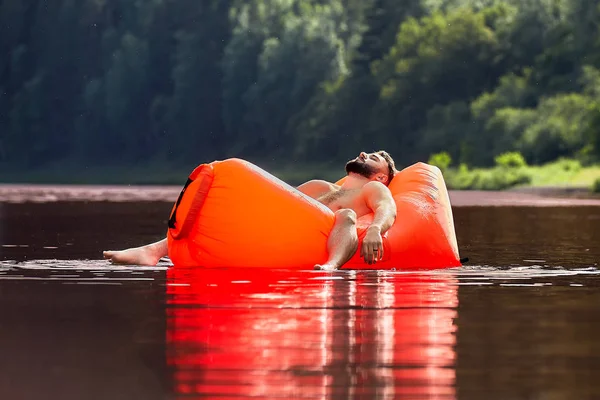 Jonge man zweeft op een opblaasbare Lounge. — Stockfoto