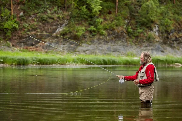 Pescador captura peces usando una varilla de mosca . —  Fotos de Stock