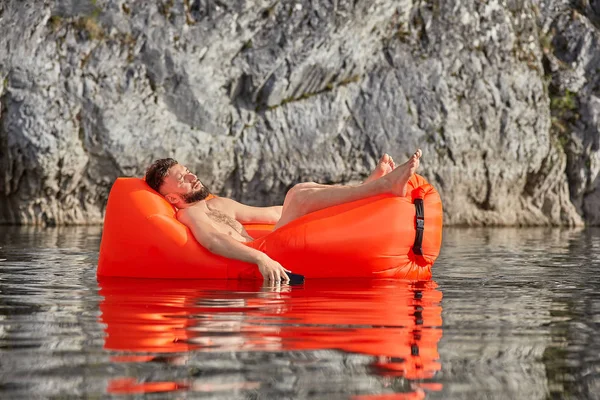 Kaukasiska man sover på airsofa med telefon. — Stockfoto