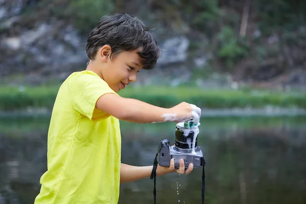 Boy cleans camera with foam. — Stock Photo, Image
