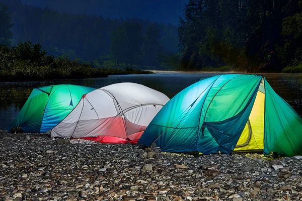 Tourist tent illuminated from inside at night.