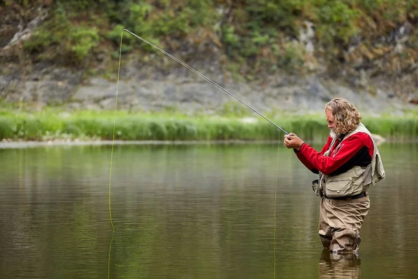 Casting pescatore catture di pesce nel fiume . — Foto Stock