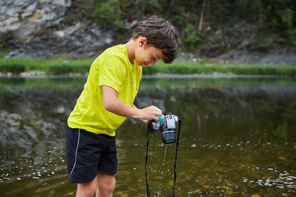 De jongen sposeert met water een digitale camera. — Stockfoto