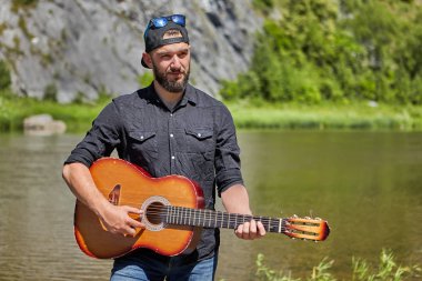 Açık havada gitar çalan genç gitarist.