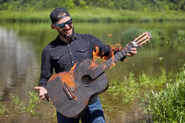 Müzisyenin elinde akustik gitar yanıyor.