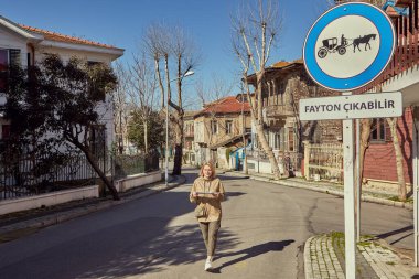 İstanbul, Türkiye - 13 Şubat 2020: Princes Adaları 'nın bir parçası olarak Büyükkada' da yürüyüş turu. Genç beyaz bir kadın bir turist haritasıyla bölgede geziniyor. Adalar bölgesine geziye giden beyaz bir kadın..