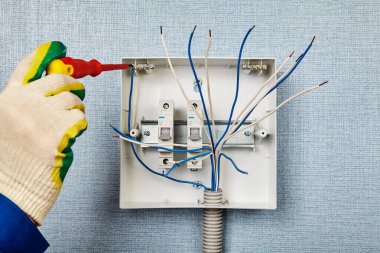 Bir santral ya da tüketici birimi kurulumu. Bir elektrikçi nötr bir bara bakır kablo bağlıyor. Kurucu, evin elektrik şebekesine bir sigorta kutusu ya da şalter yerleştirir..