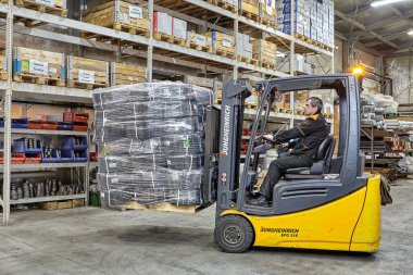 St. Petersburg, Rusya - 24 Aralık 2018: Endüstriyel ekipman deposunda malzeme taşırken forklifti sürücü kontrol ediyor. Metal fabrikasının kargo depolama sistemi.