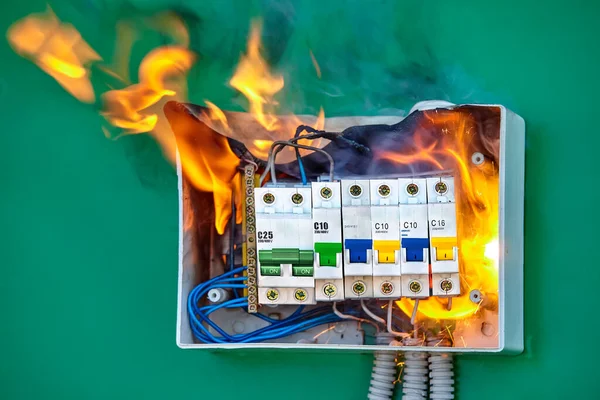 A short circuit caused an electric fire. Faulty wires led to overload of the electrical network and ignition. The distribution board in the house ignited. Burning switchboard in home.