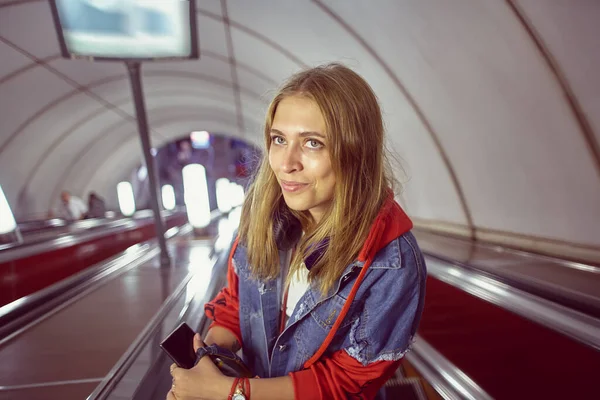 Yeraltı istasyonuna inen yürüyen merdivende bir kadın var. 20 yaşında metroda güzel bir beyaz kız..